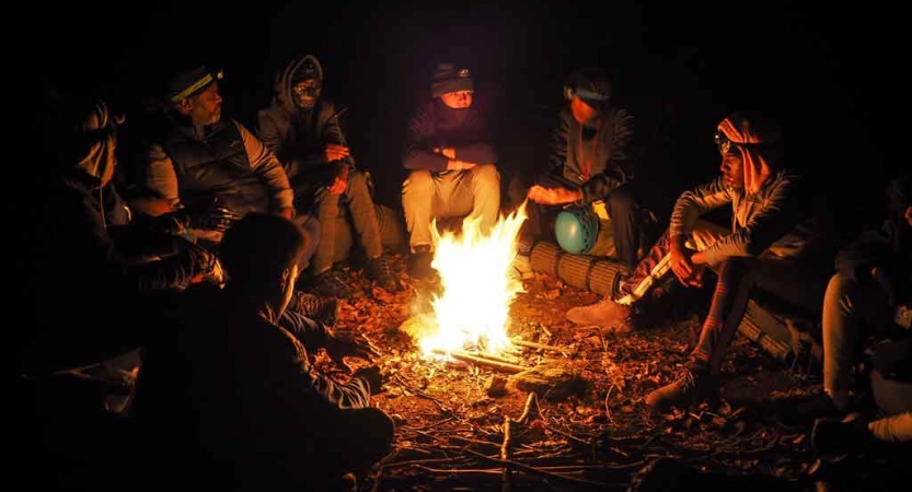 a group of teens sit around a campfire on a backpacking trip in north carolina 
